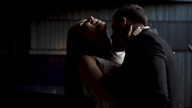 Couple shares a kiss during their wedding night at a rustic venue under soft lighting