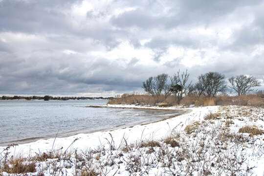 Cloudy winter day view of a snow-covered shoreline along Cape Cod Bay near Orleans, Massachusetts.