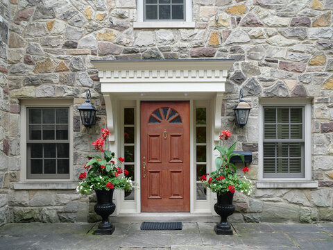 Wood grain front door of old stone house, with large flower pots
