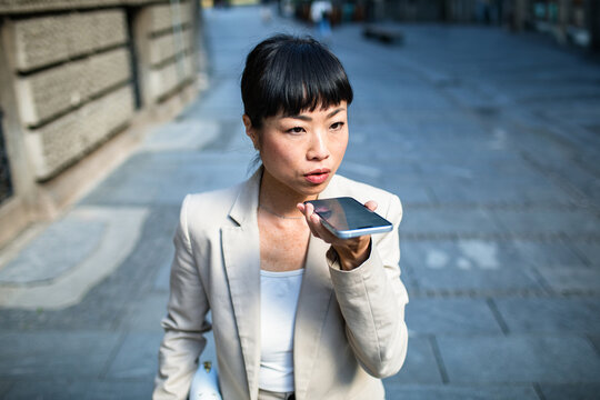 Businesswoman using voice assistant on city street
