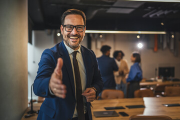 Smiling businessman offering hand for handshake in modern office © Miljan Živković