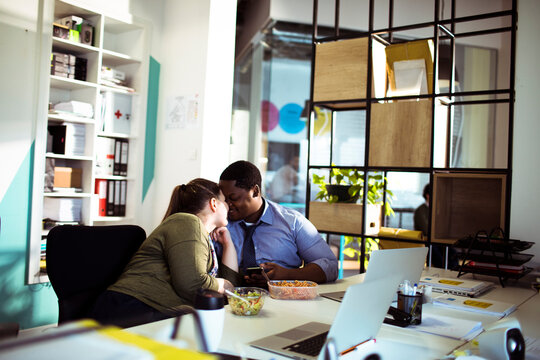 Coworkers share a kiss during office lunch break