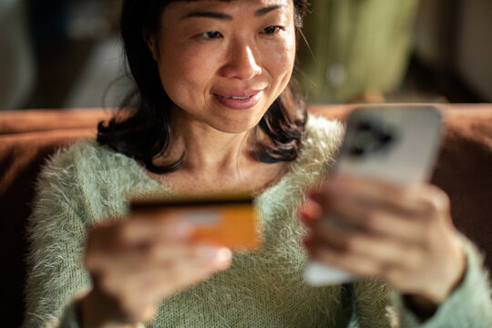 Woman paying online with smartphone at home