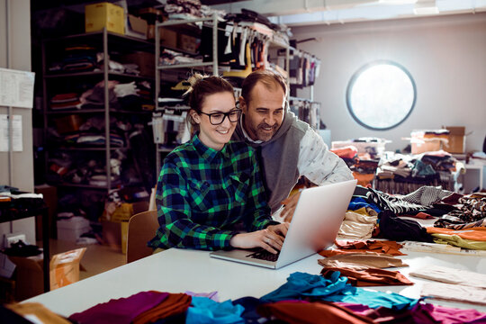 Two fashion entrepreneurs using laptop in textile workshop