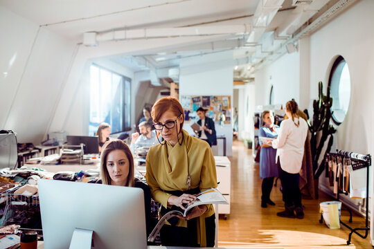 Design team collaborating at desktop computer in modern fashion studio