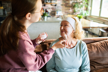 Caregiver applying face cream to senior woman at home
