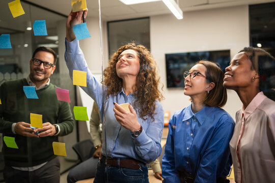 Diverse start up team brainstorming new ideas on glass wall