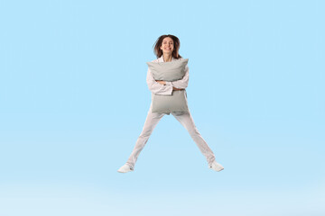 Fototapeta premium Beautiful woman in stylish pajamas with pillow posing on light blue background