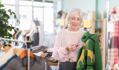 Mature woman select fashionable sweater in a clothing store