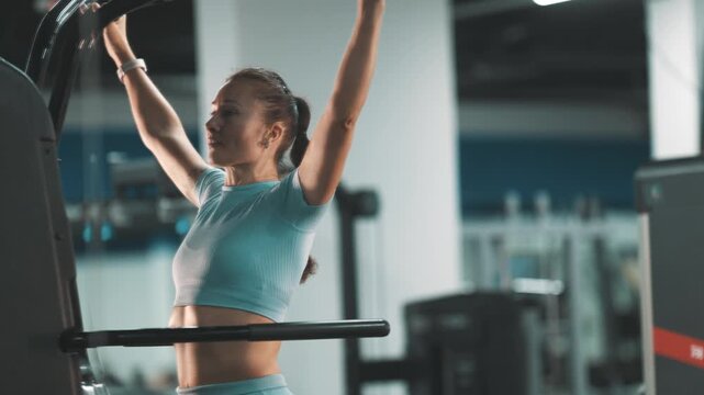 Athletic woman training back muscles on a lat pulldown machine