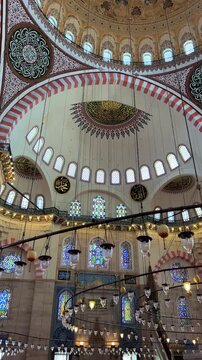 Istanbul, August 9, 2024: Inside the S&uuml;leymaniye Mosque. The prayer hall is decorated with blue tiles, stained glass windows, Quranic verses, and ornaments. The floor is covered with a large carpet.4К