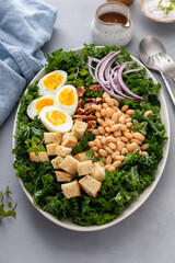 Healthy kale salad with beans, soft boiled eggs and red onion, high protein salad idea
