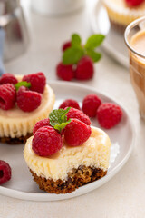 Mini cheesecakes topped with fresh raspberries on a serving plate