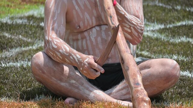 Young adult Indigenous Australians man play Aboriginal music with didgeridoo wind instrument.Aboriginal music featuring the didgeridoo (traditionally known as Yidaki or Mako) is one of the world's old