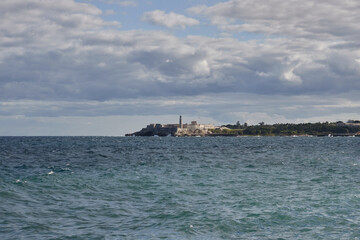 Obraz premium Panoramic view of Havana’s Malecon on a cloudy day, with rough sea waves crashing against the seawall. In the background, the urban skyline and iconic architecture of Havana facing the ocean.