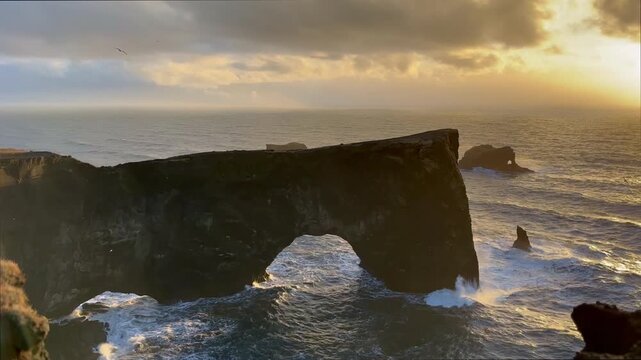Static shot of Dyrholaey stone arch and sea cliffs at sunset in winter, South Iceland. HD 1080p.