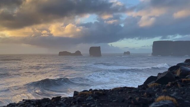 Low angle static shot of Atlantic ocean waves and sea stacks at sunset from Dyrholaey, Iceland. HD 1080p.