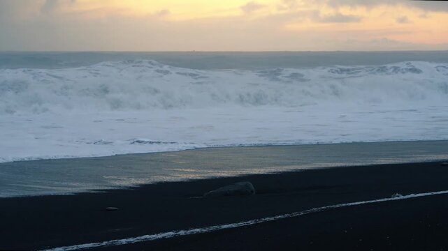 Static close-up of waves crashing on black sand beach at sunset, Iceland. HD 1080p.