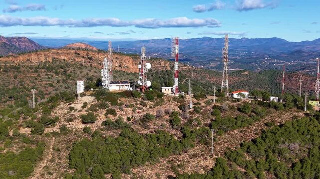 Technical orbit aerial footage of a mountain telecommunications site in Spain with lattice towers, microwave antennas and relay equipment supporting regional wireless and broadcast networks