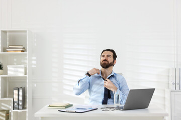 Obraz premium Man suffering from heat at table near white wall indoors, space for text