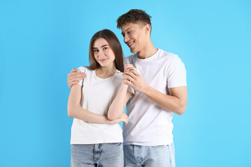 Fototapeta premium Happy couple hugging on light blue background