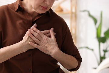 Heart attack. Senior woman suffering from pain in chest indoors, closeup. Space for text
