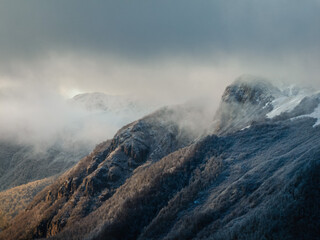 Aerial telephoto shot of snowcapped mountain peaks under clouds