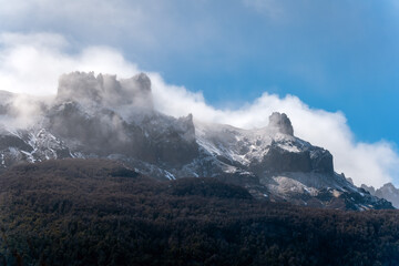 Jagged snow-capped mountain peaks with mist and clouds
