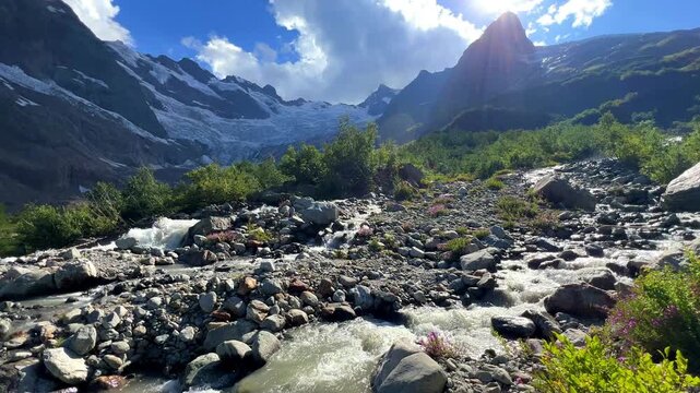 The Alibek River flows down from the Alibek Glacier, a high mountain range in Dombay, Karachay-Cherkessia, with streams of water, a snowy peak, and blocks of ice. The North Caucasus. 4К