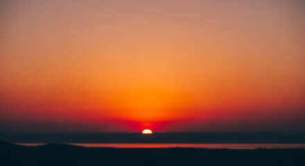 Obraz premium Blurred Vibrant Sunset over Water Horizon with Gradient Sky