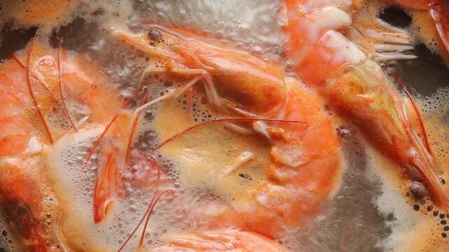 Boiling whole shell-on white shrimp in bubbling water. Top view shot