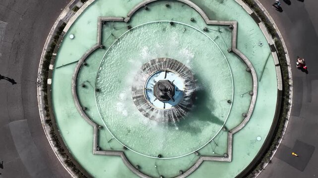 Top-down aerial over the Diana Cazadora Fountain as the drone slowly ascends, revealing cars sharing the roundabout with Sunday Ciclot&oacute;n cyclists in mexico city.