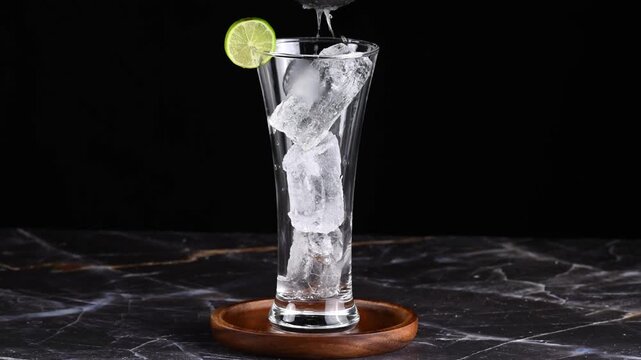 Cuba libre drink, Close-up of hands squeezing lemon juice over a glass with ice cubes to prepare a rum and coke cocktail, slow motion