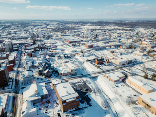 High angle aerial view of a city covered in deep white snow under a bright clear blue sky.