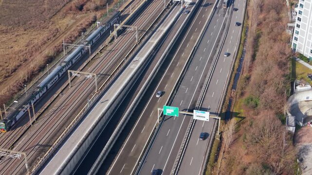 Urban Transport Convergence: An aerial vista unfolds, showcasing a dynamic confluence of transport systems - railway and motorway - coexisting in a bustling cityscape. 
