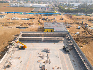 Aerial view of a large-scale construction site with heavy machinery and industrial building progress.ult