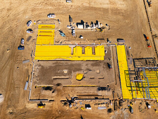 Aerial view of a large-scale construction site with heavy machinery and industrial building progress.ult