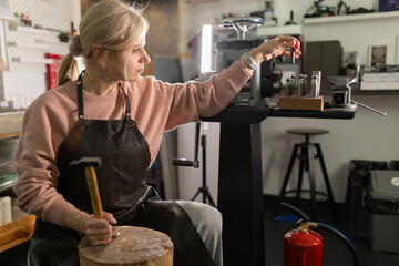 Skilled female artisan working carefully with metal tools in workshop