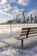 Naklejka premium Icicles forming on a rail at a frozen pier - Toronto skyline in the background from Polson Pier