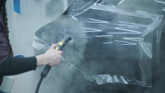 Professional detailer installing Paint Protection Film (PPF) on car B-pillar. Close-up of hands using squeegee and knife to apply transparent anti-gravel vinyl.