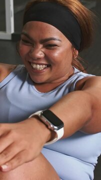 Vertical video: Starting woman crunching at gym after partner arriving, wearing blue top, watch