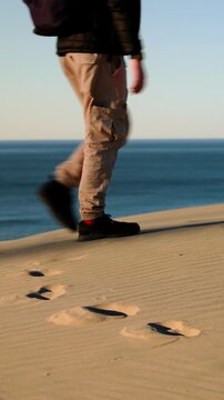 Person walks along golden sand dune above Namibia Coast, leaving footprints in soft sand, symbolizing travel, freedom, movement, and peaceful coastal adventure. Africa