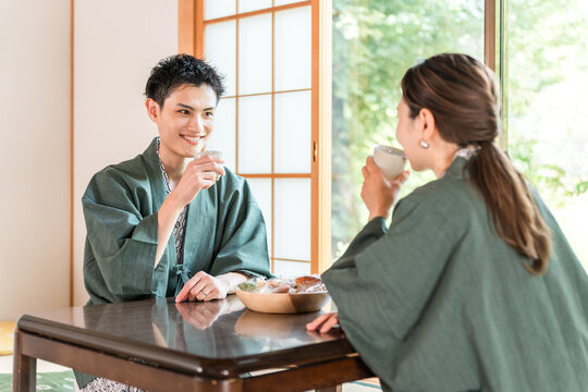 A couple in yukata drinking tea in a Japanese-style room at a ryokan with a garden view