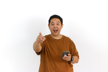 Naklejka premium An Asian male individual reacting with a winning gesture and excited facial expression while using a smartphone.