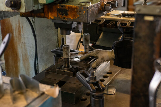 Manual metal press operation with worker hand positioning industrial jig