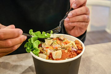 Close-up of a person eating chicken katsu rice bowl with sambal matah using a spoon and fork