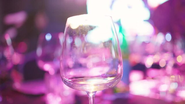 Festive environment displaying unfilled wine glass along with colorful illumination and confetti remnants