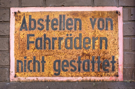 Weathered German sign "Abstellen von Fahrr&auml;dern nicht gestattet" -prohibiting bicycle parking- on a historic industrial building in Cologne. Grungy metal texture and rust