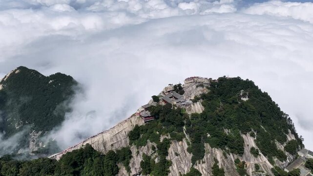 Aerial top-down video of the West Peak and green dragon ridge at Mount Hua, with tourists walking along narrow cliffs above a sea of clouds, Shaanxi province, China