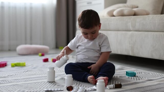 Child safety at home. Little boy playing with pills on floor indoors